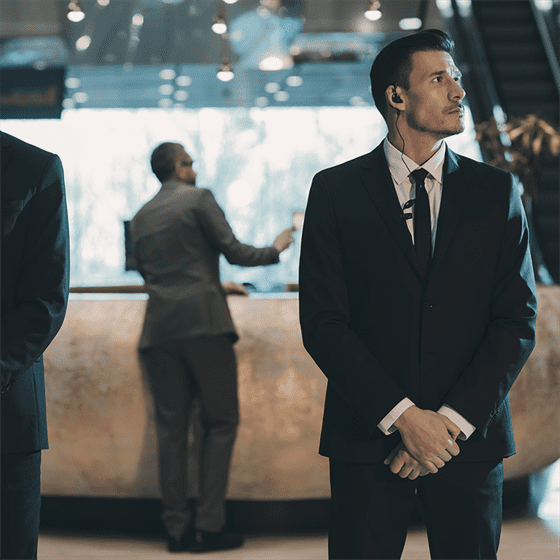 three men in suits standing in a lobby.