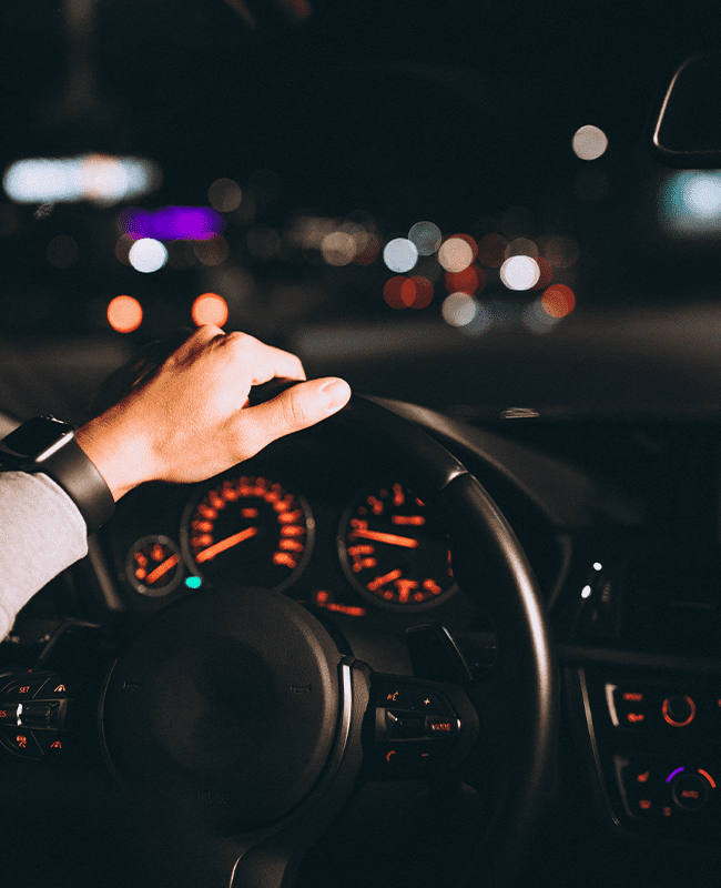 A man providing driver services in Houston, driving a car at night.