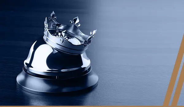 a silver crown on top of a table bell that is placed on a wooden table.