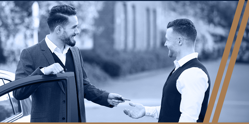 a well-dressed gentle man and a valet attendants exchange car keys outside a corporate event, showcasing reliable valet services in Bellaire.